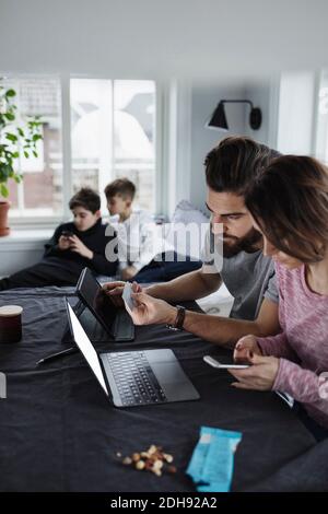 Mother and father shopping online with sons in living room at home Stock Photo