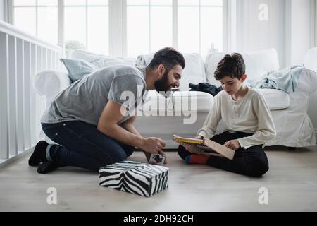 Father looking at boy using abacus in living room Stock Photo