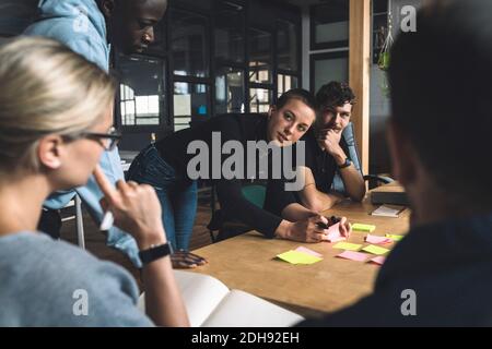Female freelancer discussing with colleagues over start-up strategy at workplace Stock Photo