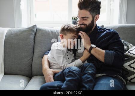 Father and son while sitting on sofa at home Stock Photo