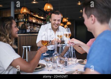 Happy colleagues raising toast during business lunch at restaurant Stock Photo