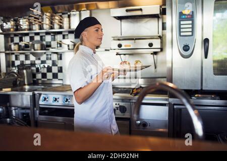 Female chef serving food in kitchen at restaurant Stock Photo