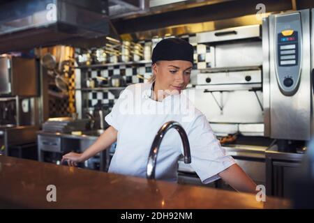 Young female chef working in kitchen at restaurant Stock Photo