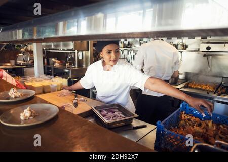 Female chef preparing food in kitchen at restaurant Stock Photo