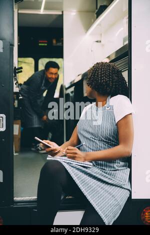 Female owner talking to assistant in food truck Stock Photo