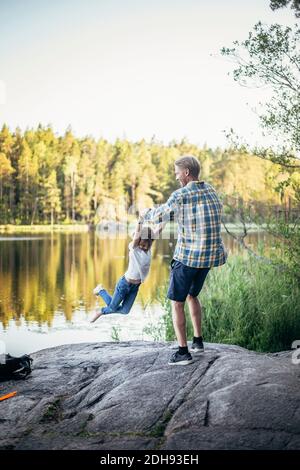 Happy father spinning daughter at lake Stock Photo