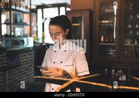 Female chef using smart phone in restaurant Stock Photo
