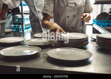 Midsection of chef arranging plates at kitchen counter Stock Photo