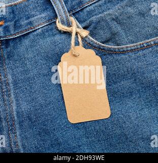 Blank brown rectangular tag tied in the back pocket of blue folded jeans Stock Photo