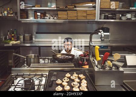 Male chef cooking mushrooms in commercial kitchen Stock Photo