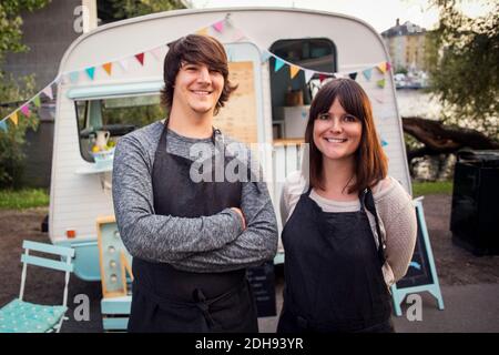 Portrait of happy owners standing on street against food truck Stock Photo