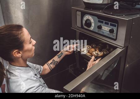 High angle view of female chef baking mushrooms in oven Stock Photo