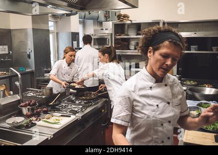 Chefs preparing food in kitchen at restaurant Stock Photo