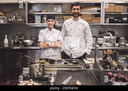 Portrait of smiling male and female chefs in commercial kitchen Stock Photo