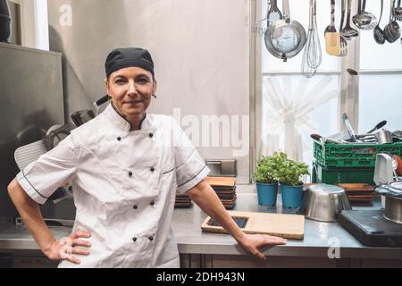 Portrait of confident mature chef with hand on hip in commercial kitchen Stock Photo