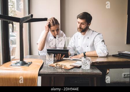Chef with coworker looking at digital tablet at table in restaurant Stock Photo