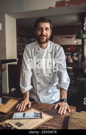 Portrait of confident chef standing by table in restaurant Stock Photo