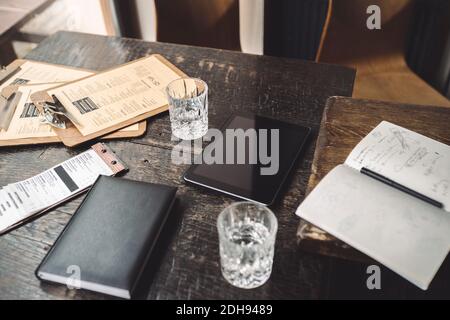 High angle view of drinking glass with diary and digital tablet on table in restaurant Stock Photo