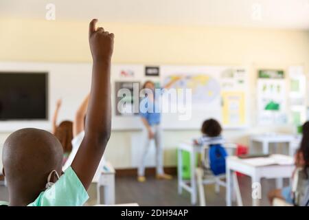 Students raising hands in class at school Stock Photo