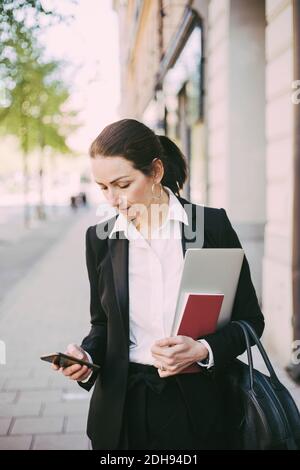 Businesswoman using smart phone in city Stock Photo