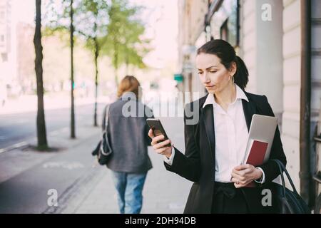 Businesswoman using mobile phone in city Stock Photo