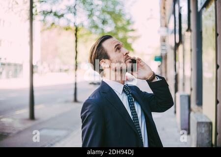 Side view of businessman talking on phone in city Stock Photo