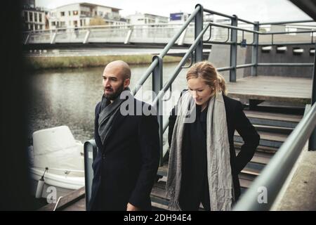 Mid adult businessman and businesswoman walking down stairs by river Stock Photo