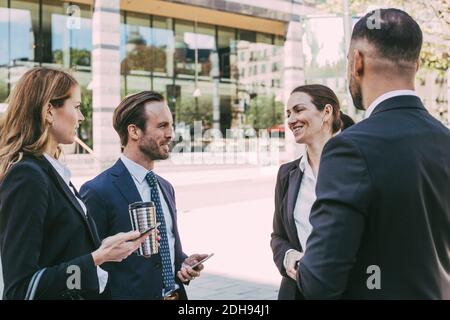 Smiling female entrepreneur talking to colleagues in city Stock Photo