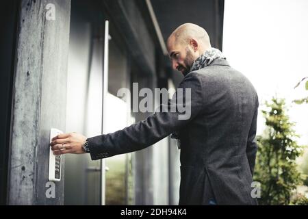 Side view of mid adult businessman entering keycode to open office door Stock Photo