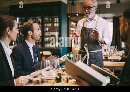 Waiter talking to business people in restaurant Stock Photo