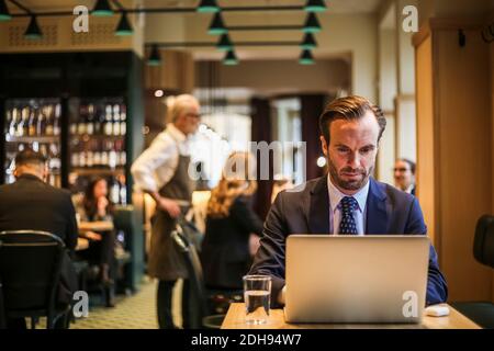 Businessman using laptop while sitting in restaurant Stock Photo