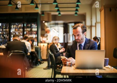 Businessman using mobile phone while sitting in restaurant Stock Photo