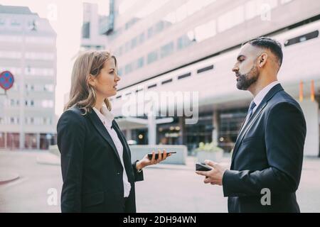 Side view of businesswoman talking to businessman in city Stock Photo