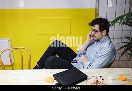Young man using smart phone while sitting at desk in board room Stock Photo