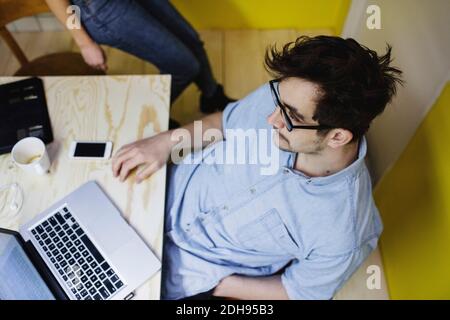 High angle view of young man sitting with laptop at desk in office Stock Photo