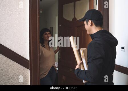 Smiling customer talking to delivery man at doorstep Stock Photo