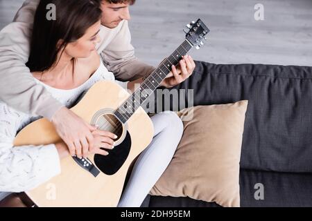 High angle view of young man teaching girlfriend to playing acoustic guitar at home Stock Photo