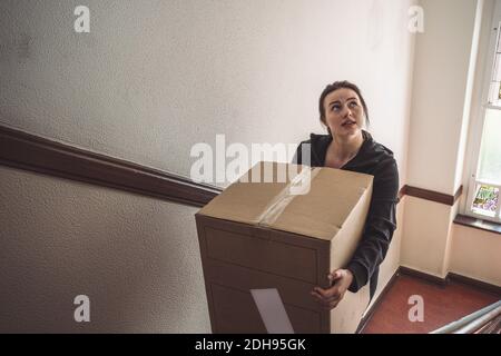 High angle view of delivery woman with cardboard box climbing steps Stock Photo