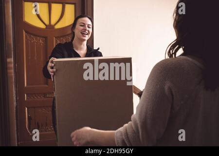 Smiling delivery woman making home delivery to female customer at doorstep Stock Photo