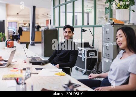 Smiling young man looking at female colleague in creative office Stock Photo