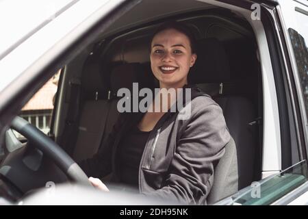 Portrait of smiling delivery woman sitting in truck Stock Photo