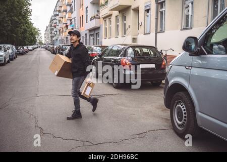 Confident delivery man with package walking on street in city Stock Photo