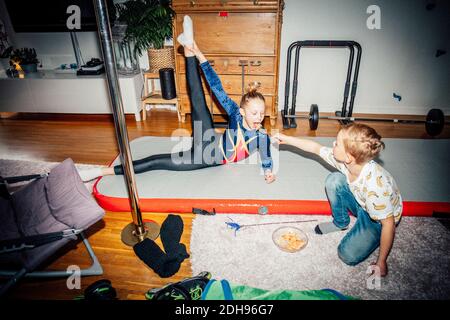 Girl practicing while brother feeding sister in living room Stock Photo
