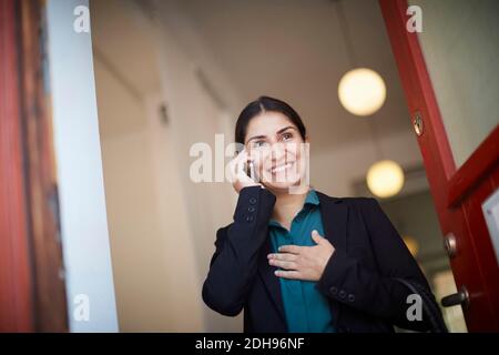 Smiling businesswoman talking on mobile phone in office Stock Photo