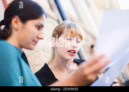 Mid adult businesswomen discussing over documents outside office Stock Photo