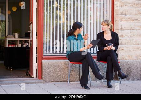 Full length of businesswoman discussing with female colleague outside office Stock Photo