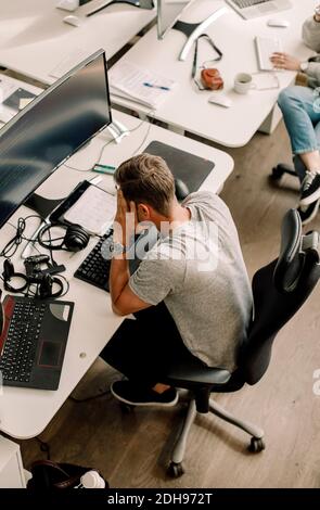 High angle view of computer programmer sitting at table in office Stock Photo