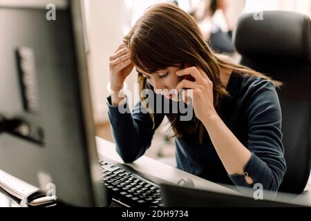 Computer programmer talking on phone at workplace Stock Photo