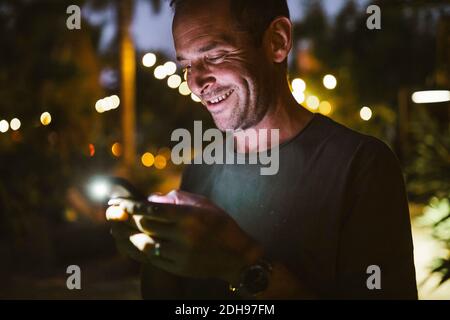Smiling man texting during sunset Stock Photo