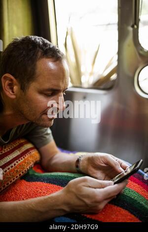 Mature man using phone in camper trailer Stock Photo